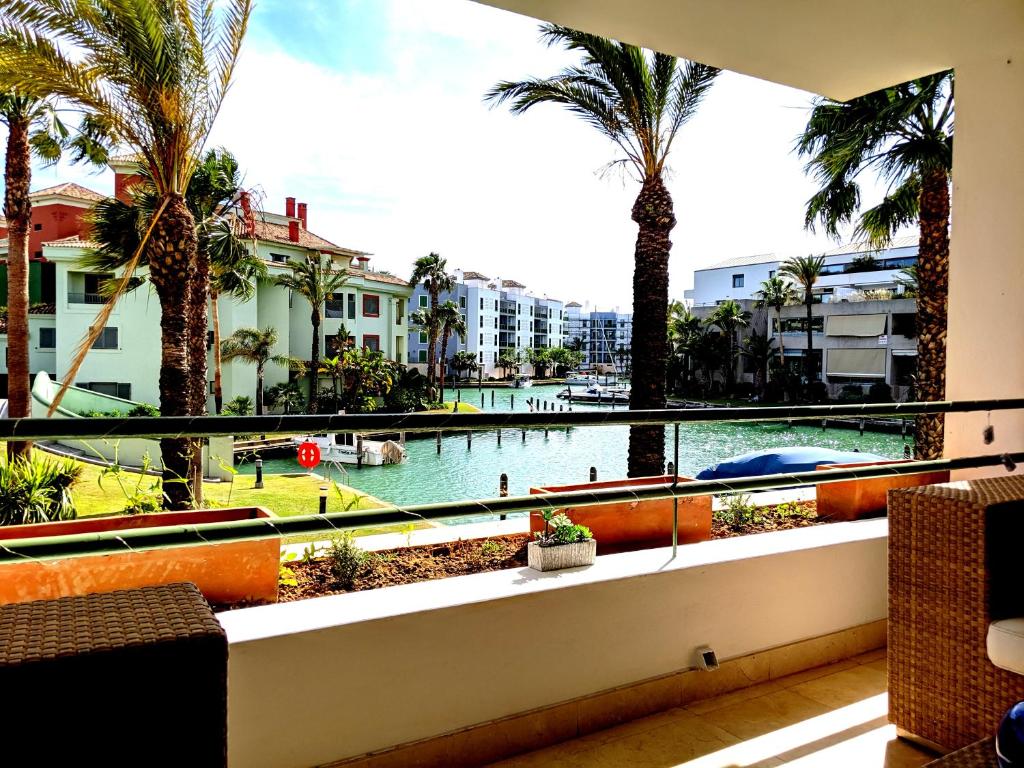 balcón con vistas a la piscina y a las palmeras en Polo Royale Waterfront Luxury Apt - 3 terraces and pool, en Sotogrande