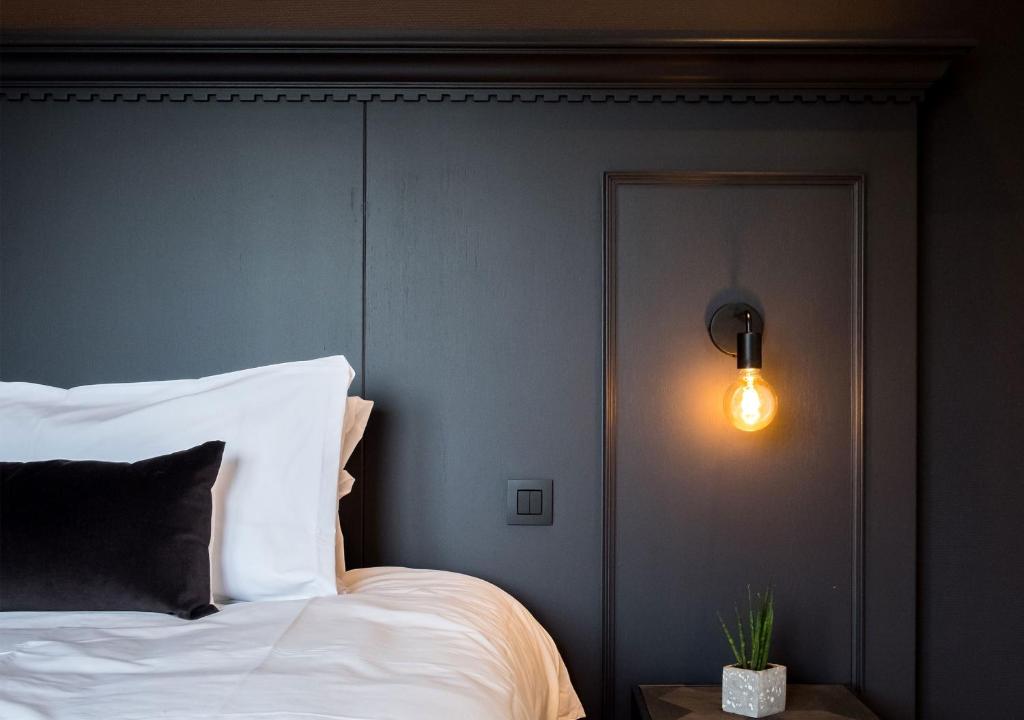 ein Schlafzimmer mit einem Bett und einer Lampe an der Wand in der Unterkunft ENSO - Boutique Hotel in Knokke-Heist
