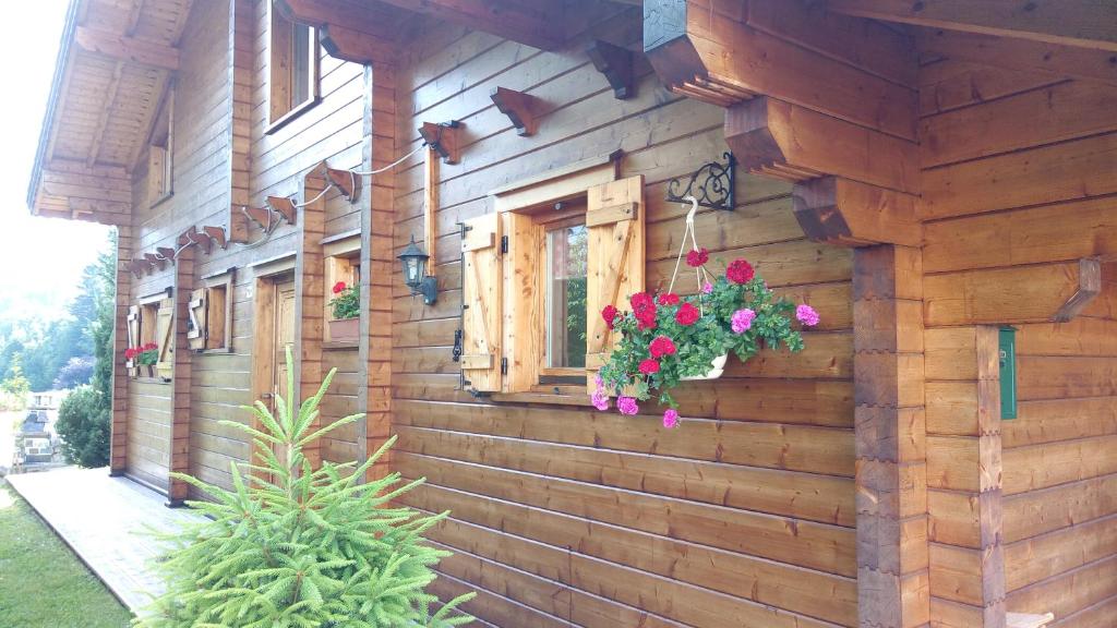 une maison en bois avec une fenêtre ornée de fleurs dans l'établissement Le Chalet de Philippe, à La Bresse