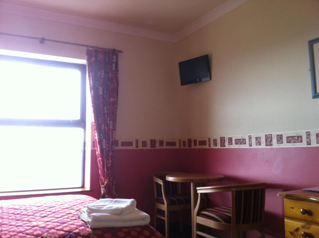 a bedroom with a bed and a tv on the wall at Pier House Bed & Breakfast in Inis Mor