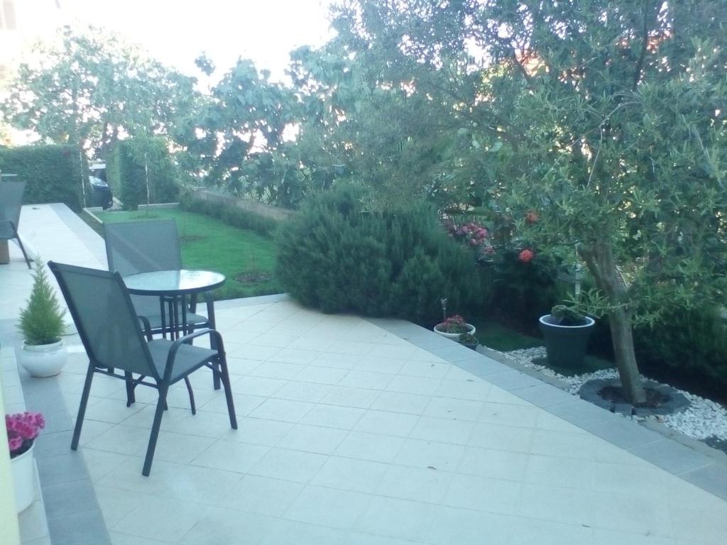 a patio with a table and chairs and trees at Ana Rooms in Krk
