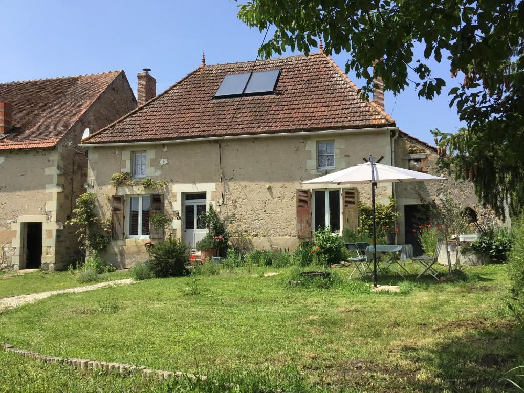 an old house with an umbrella in the yard at Le Domaine in Lignac