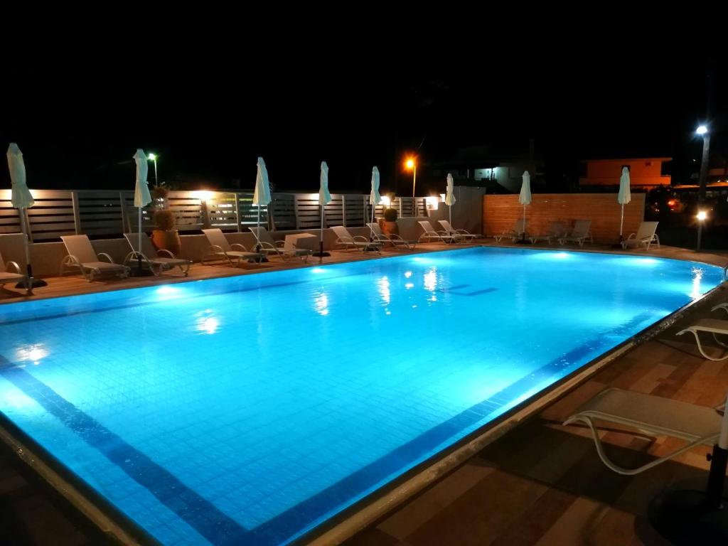 a swimming pool at night with chairs and umbrellas at IVORY HOTEL in Theologos