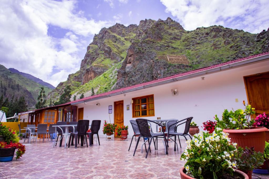 eine Terrasse mit Stühlen und Tischen vor einem Berg in der Unterkunft Intitambo Hotel in Ollantaytambo