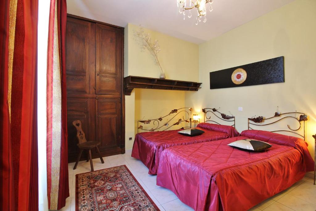 a bedroom with two beds with red sheets and a chandelier at Dolwin in Argelès-Gazost