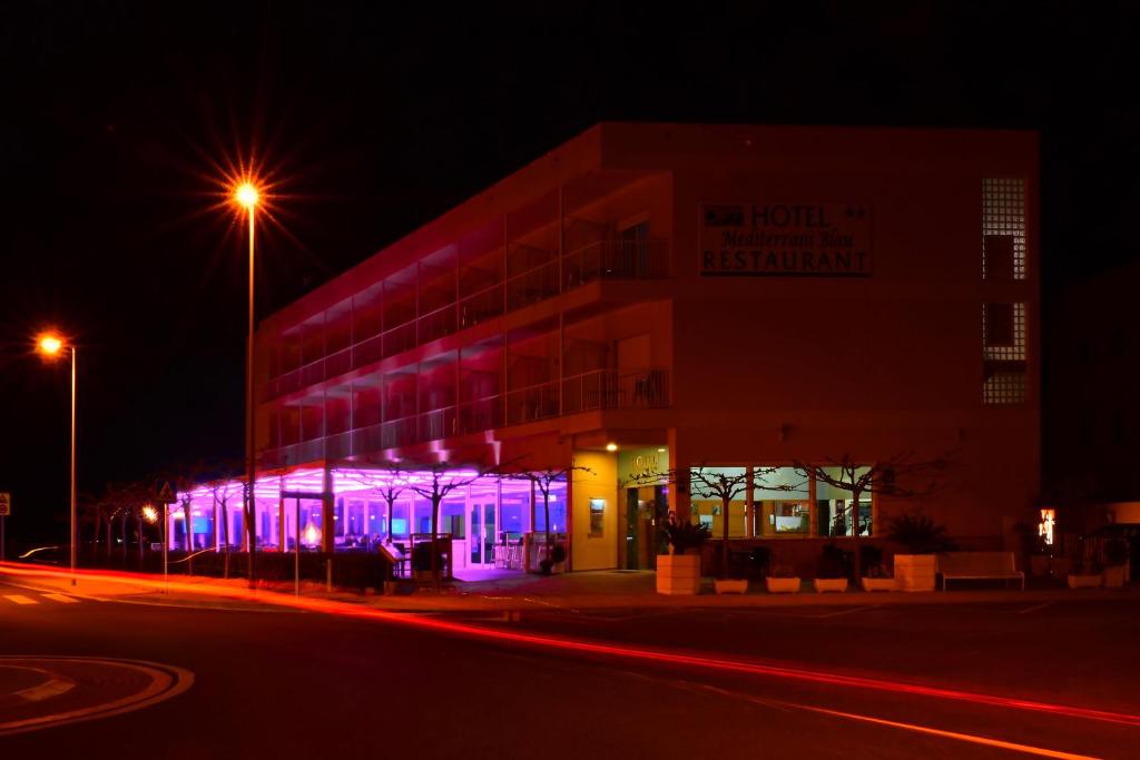 un edificio con luces moradas en él por la noche en Hotel Mediterrani Blau, en Sant Jaume d'Enveja