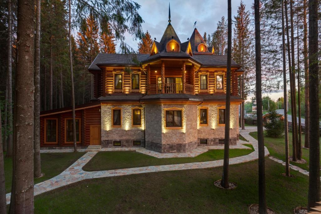 a large wooden house in the middle of a forest at Okhotnichyi sezony Hotel in Polazna