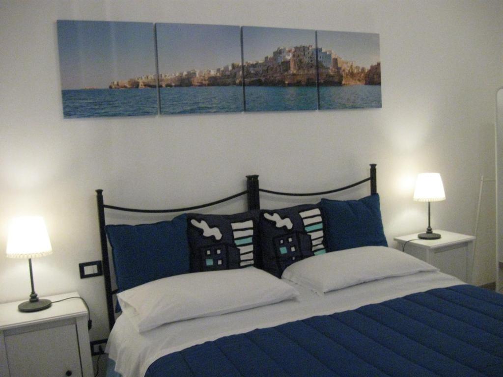 a bedroom with a blue bed with three paintings on the wall at Il mare in un Boccaccio in Polignano a Mare
