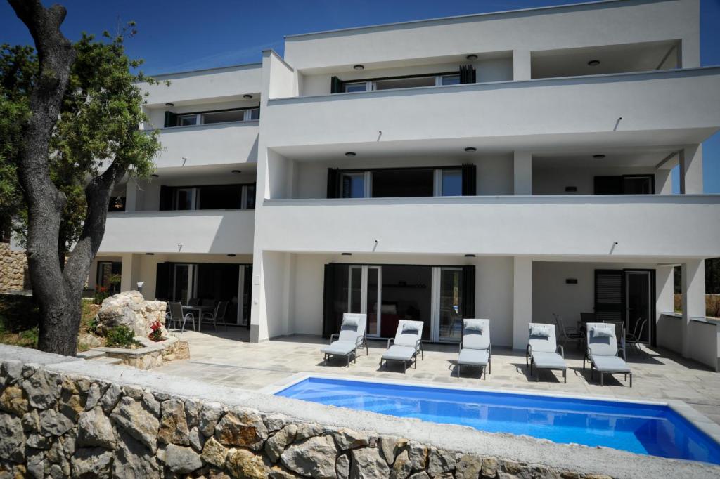 a villa with a swimming pool in front of a building at Apartments Novak in Rab