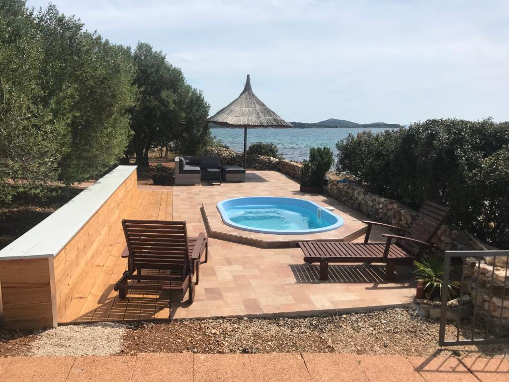 a backyard with a pool and chairs and a table at Modrave Robizon in Murter