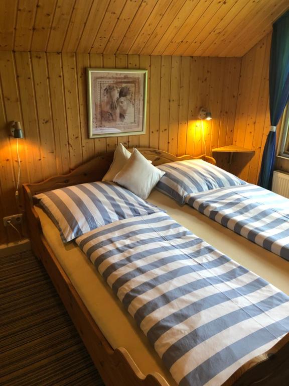 two beds in a room with wooden walls at Hof Keske in Peissen