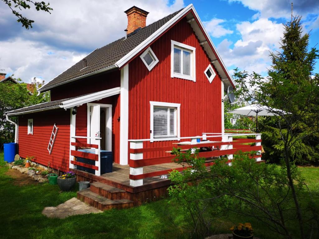 a red house with a porch on a yard at Ferienhaus Heidi in Rosenfors