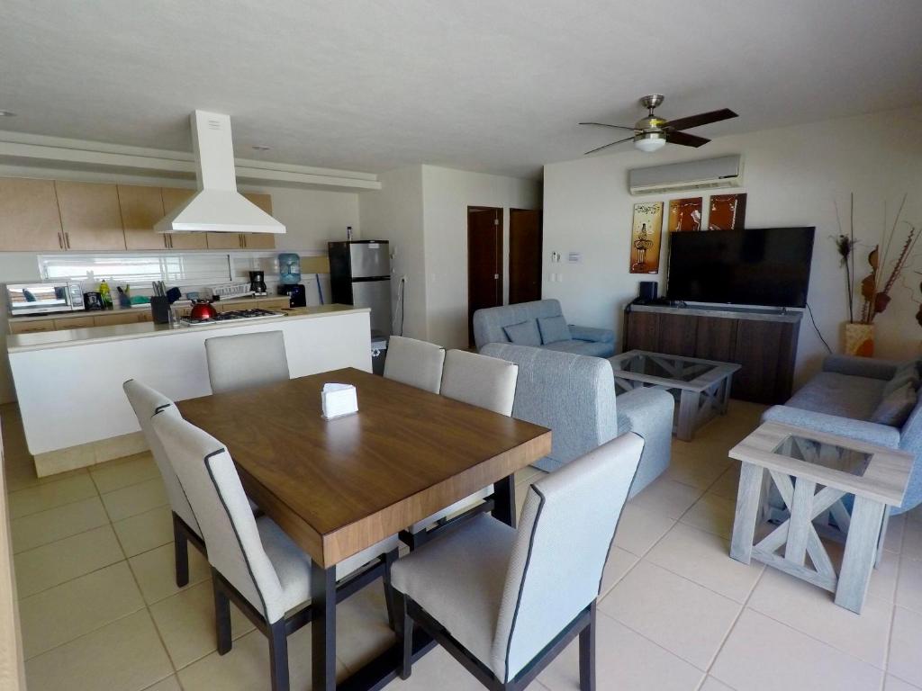 cocina y sala de estar con mesa de madera y sillas en 3 Bedroom Apartment at La Joya Hotel Zone, en Puerto Vallarta
