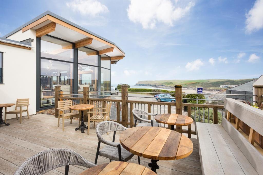 una terraza con mesas y sillas y vistas al agua en Oystercatcher Apartments en Polzeath