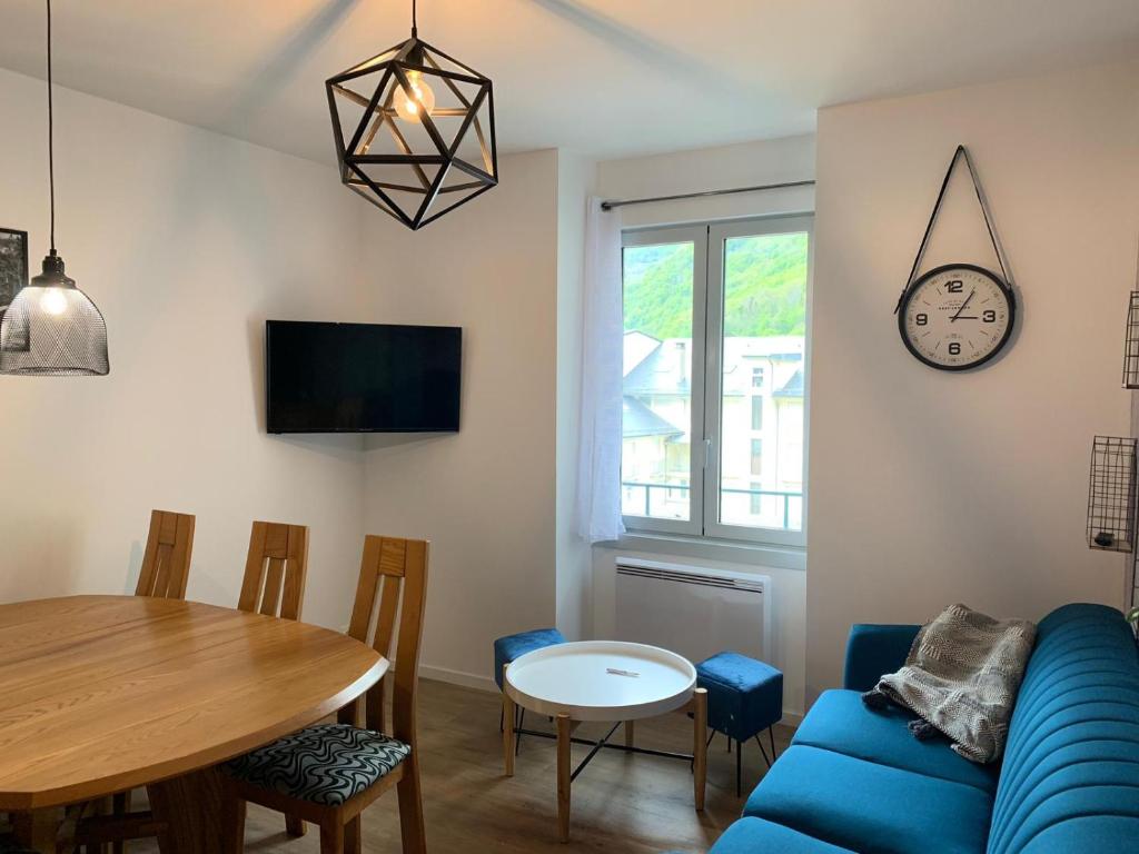 a living room with a blue couch and a table at Appartement rénové & calme - Centre-ville 4 à 6 Pers - 2eme Étage Cuisine Équipée- Linge et Ménage en option in Cauterets