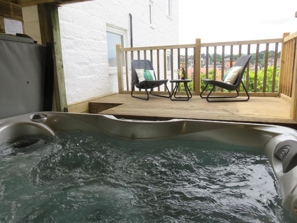 a hot tub on a deck with two chairs and a table at Esk Cottage - Cyanacottages in Whitby
