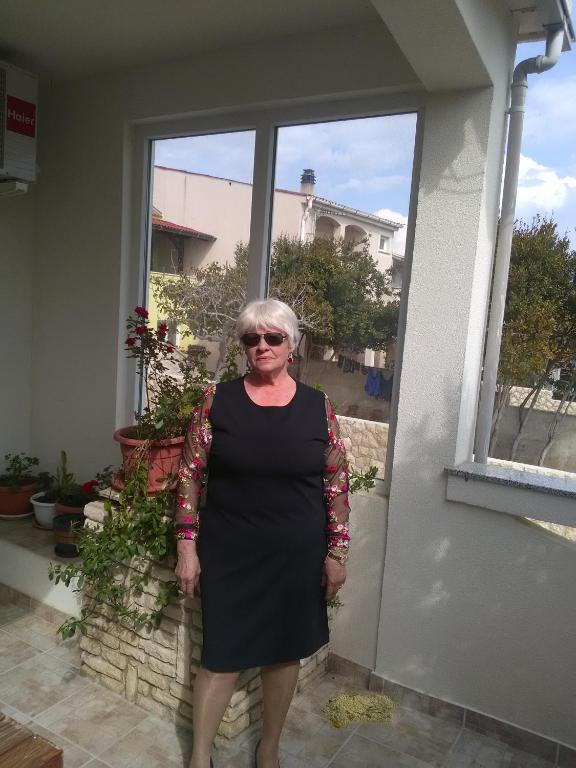 a woman in a black dress standing in front of a window at Apartment Tičić in Povljana