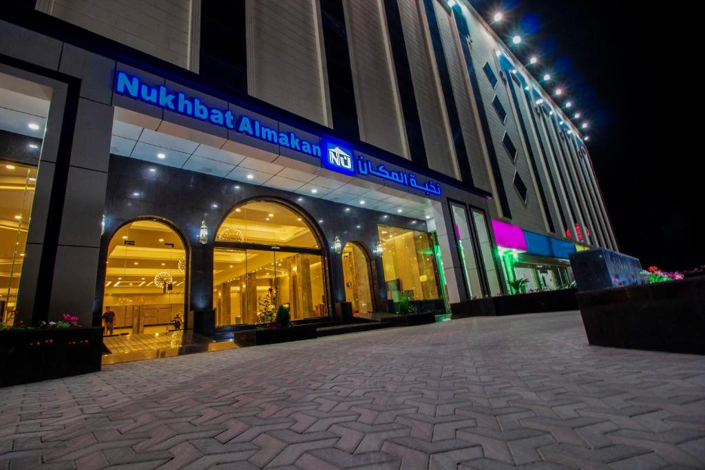 a shopping mall with a sign on it at night at Nukhbat Al Makan Apartment Hotel in Taif