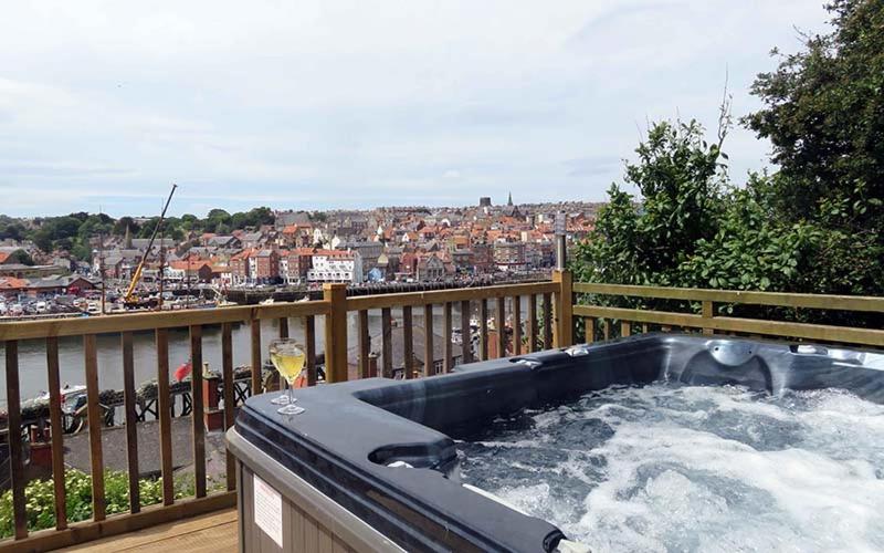 a hot tub on a deck with a view of a city at Ropery Cottage - Cyanacottages in Whitby