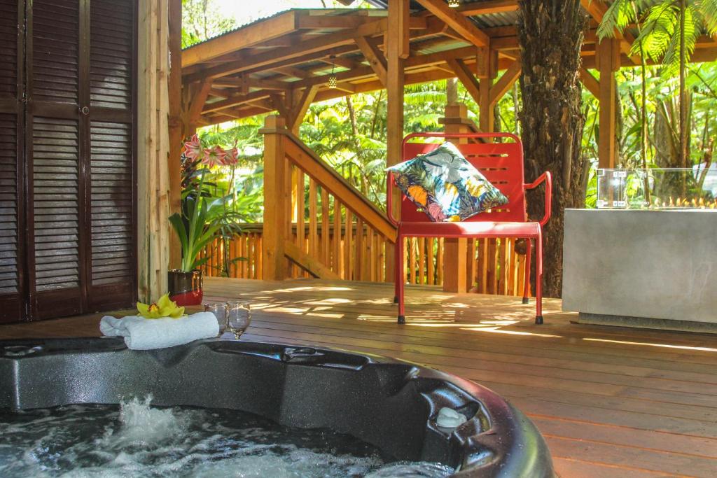 a hot tub on a deck with a red chair at At the Craters Edge in Volcano