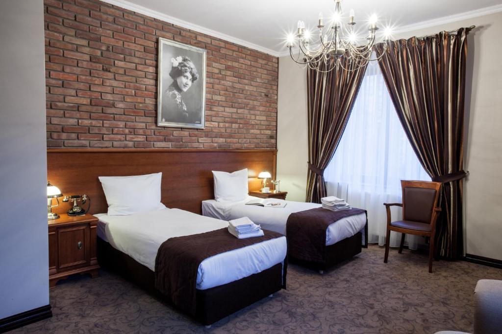 a hotel room with two beds and a brick wall at Trzy Korony Boutique Hotel&SPA Piwne in Puławy