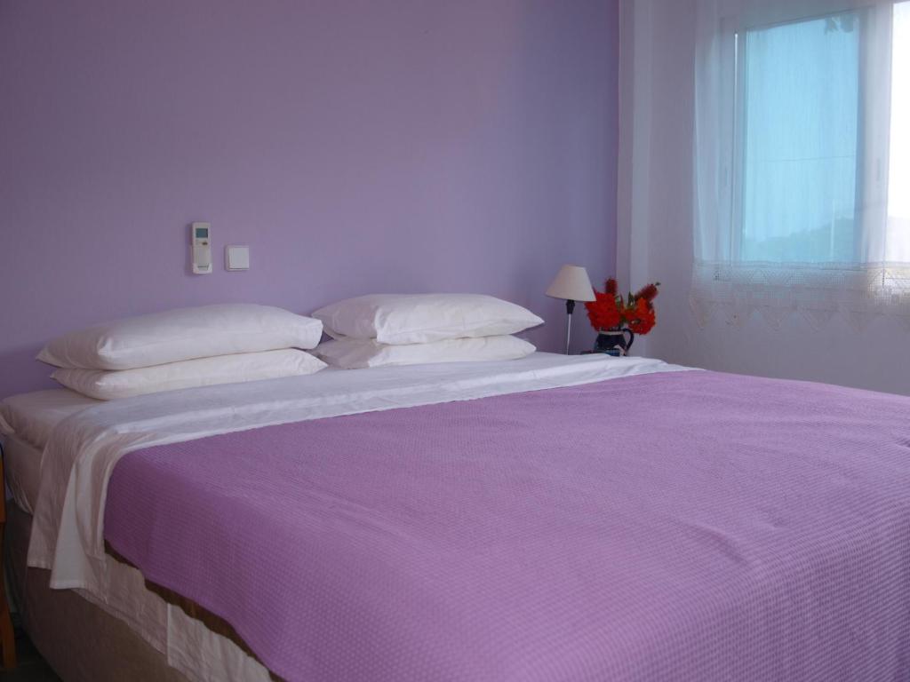 a bedroom with a large bed with purple sheets and pillows at Ikion Studios in Steni Vala Alonissos
