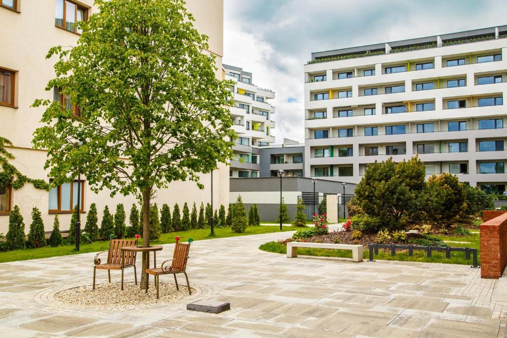 a table and two chairs under a tree in a courtyard at The Town Hall Residence -Welcome Home Apartment-free outdoor parking-AC in Košice