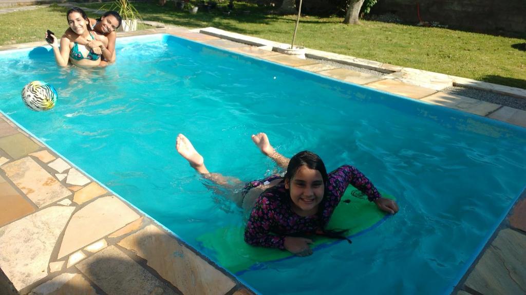 drie meisjes liggen in een zwembad bij Casa Aconchegante Lazer e Descanso in Araruama
