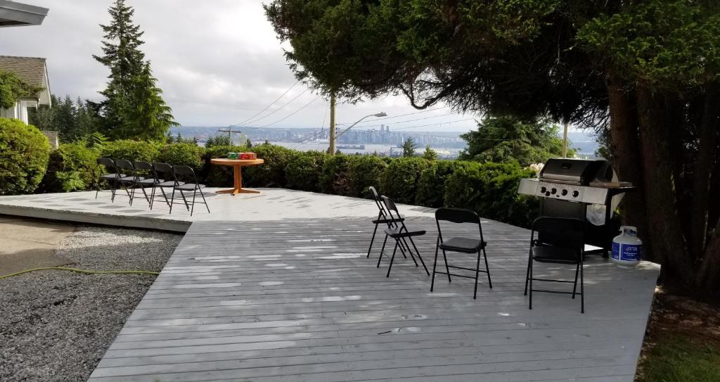 eine Terrasse mit Stühlen, einem Grill und einem Tisch in der Unterkunft City Gardens Suites B&B in North Vancouver