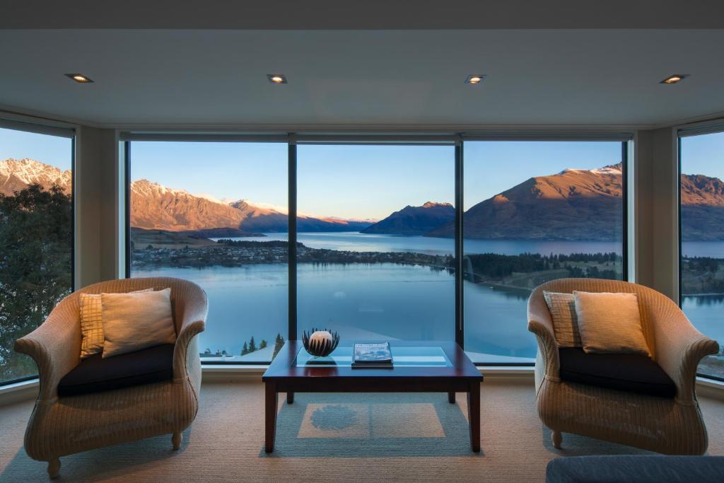 a living room with two chairs and a table and a large window at Majestic View Home in Queenstown