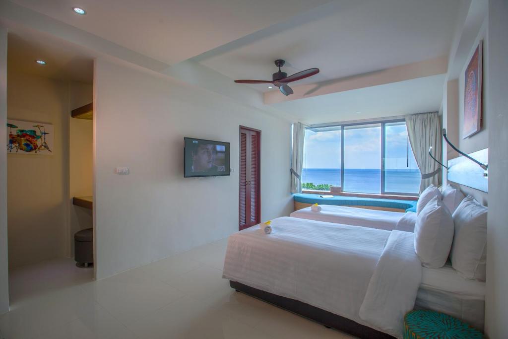 a bedroom with a bed with a view of the ocean at Norn Talay Surin Beach Phuket in Surin Beach