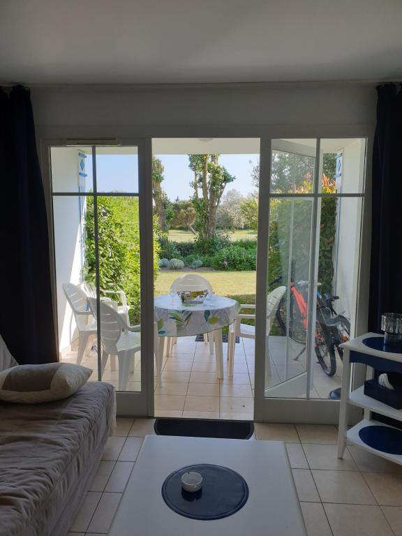 een woonkamer met een glazen schuifdeur naar een patio bij Appartement vue sur golf in Talmont