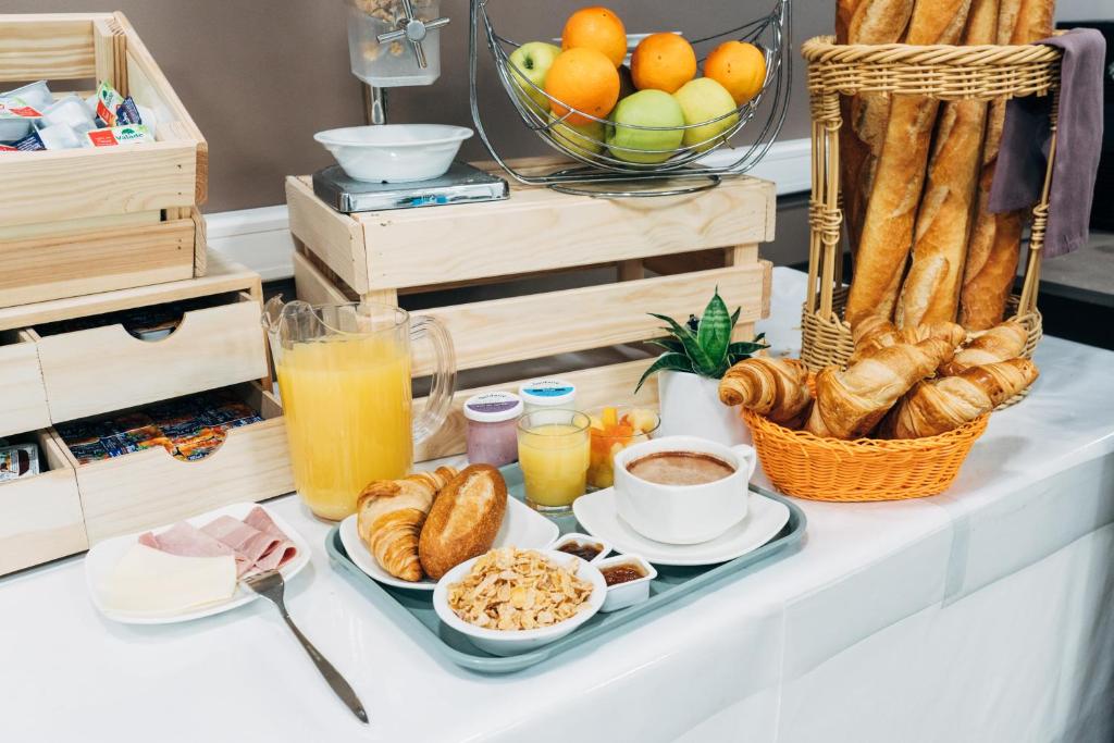 a breakfast tray with croissants and other breakfast foods at Hôtel Hélianthe in Lourdes