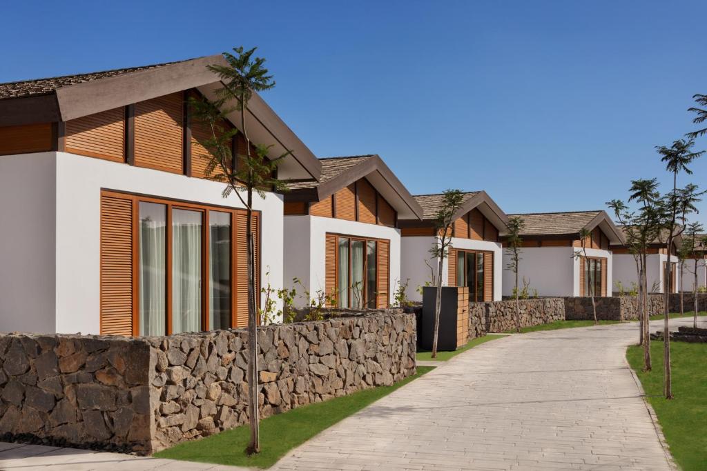 a row of houses with a stone wall and a sidewalk at The Setai Sea Of Galilee in Ein Gev