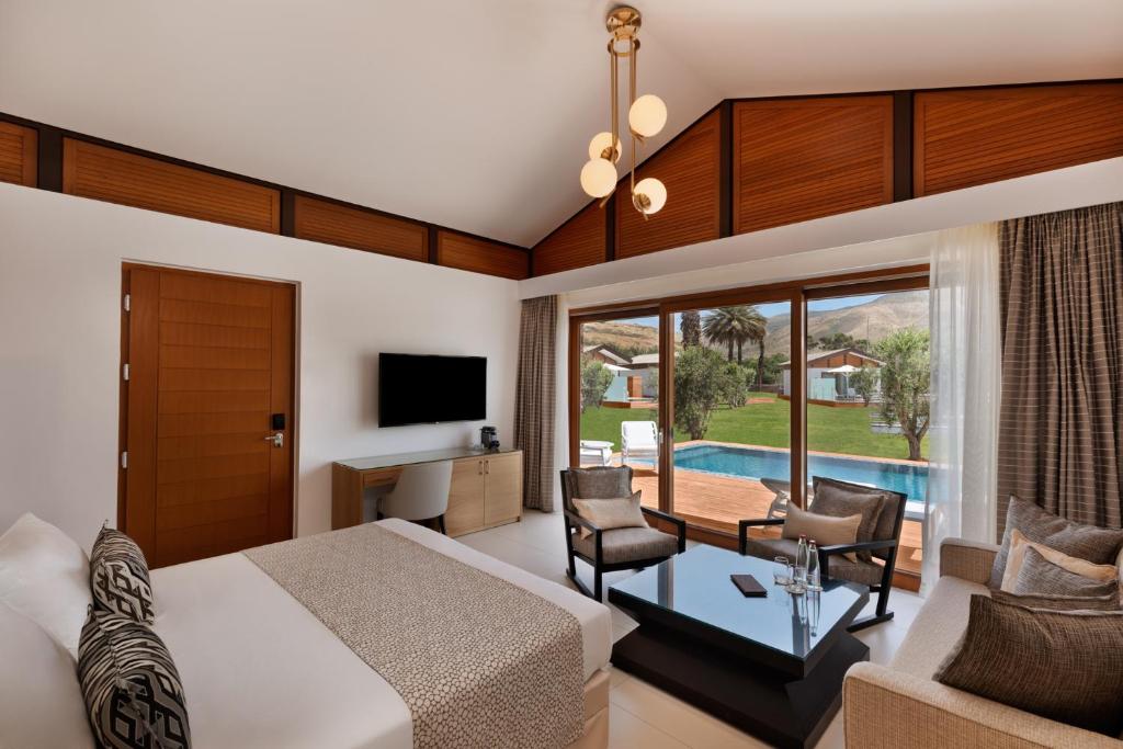 a bedroom with a bed and a desk and a tv at The Setai Sea Of Galilee in Ein Gev