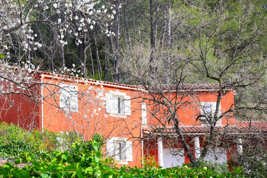 um edifício laranja com janelas e árvores brancas em Le Relais du Gapeau em Solliès-Toucas