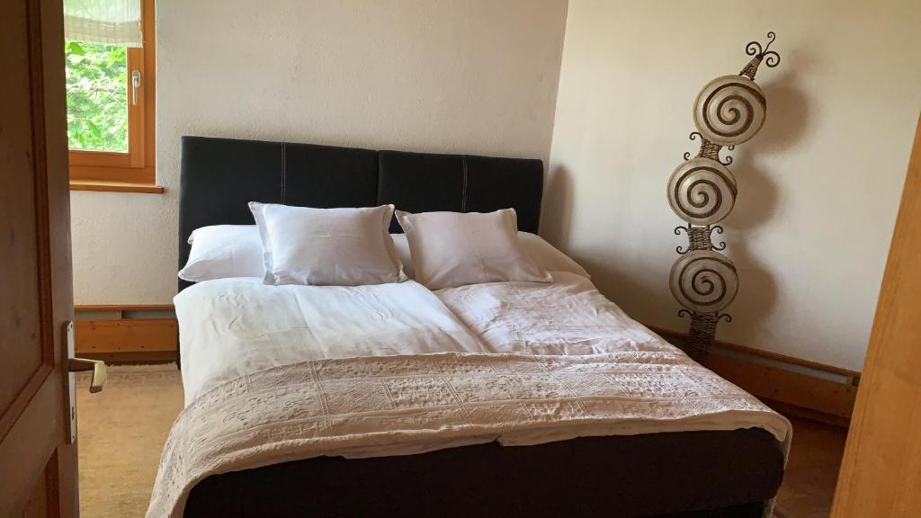 un letto con lenzuola e cuscini bianchi in una camera da letto di Bed & Breakfast Region Murtensee a Münchenwiler