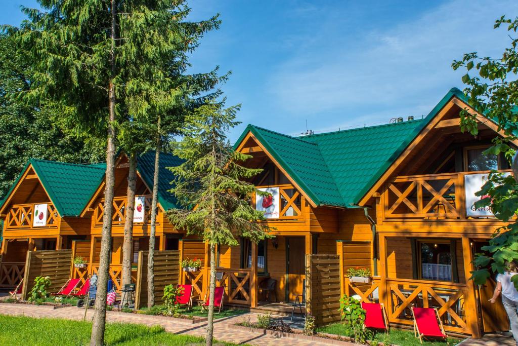 a wooden house with red chairs in front of it at Domki pod lasem blisko morza in Sztutowo