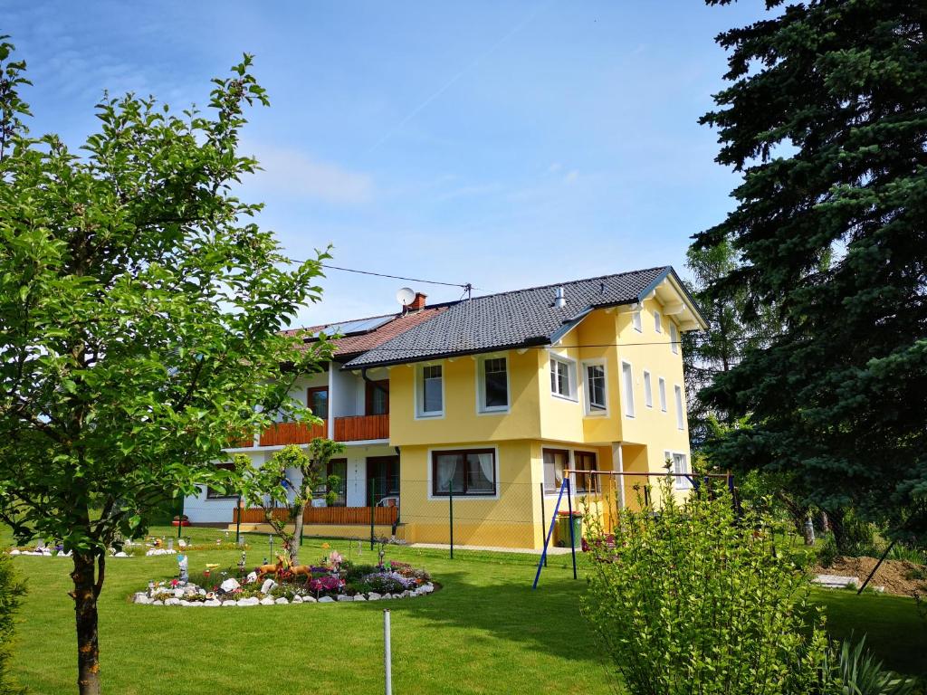 une maison jaune avec un jardin dans la cour dans l'établissement Pension Eule, à Sankt Kanzian