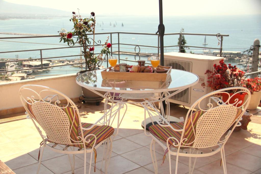 een tafel en stoelen op een balkon met uitzicht op de oceaan bij Piraeus Lux Secret in Piraeus