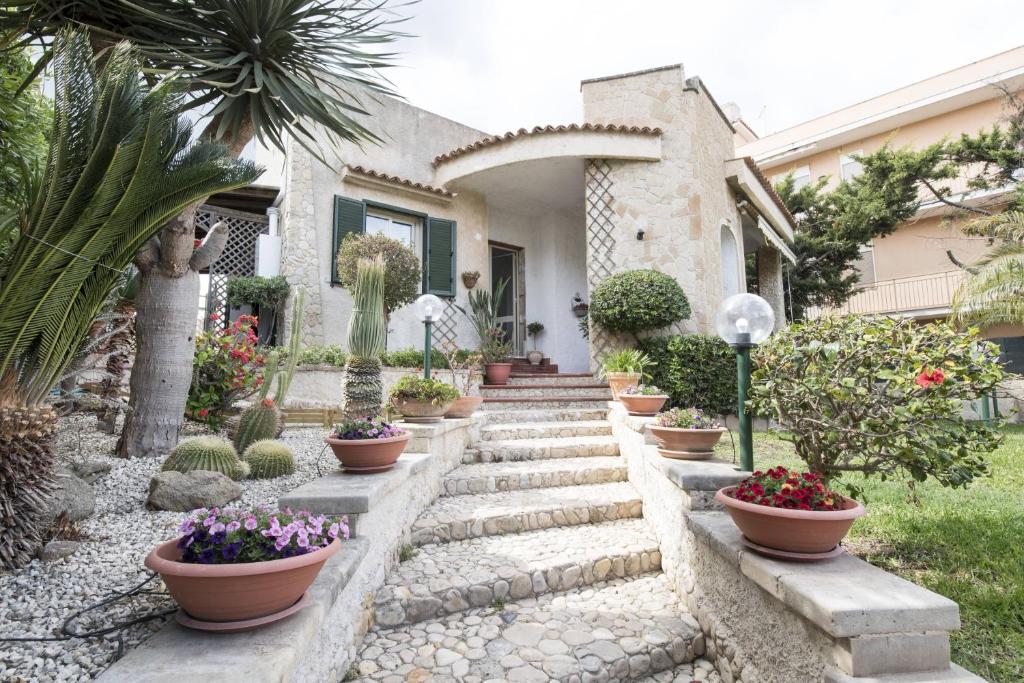 un jardin avec des plantes en pot et une maison dans l'établissement Venti del Sud Appartamenti Affitti Brevi, à Noto Marina