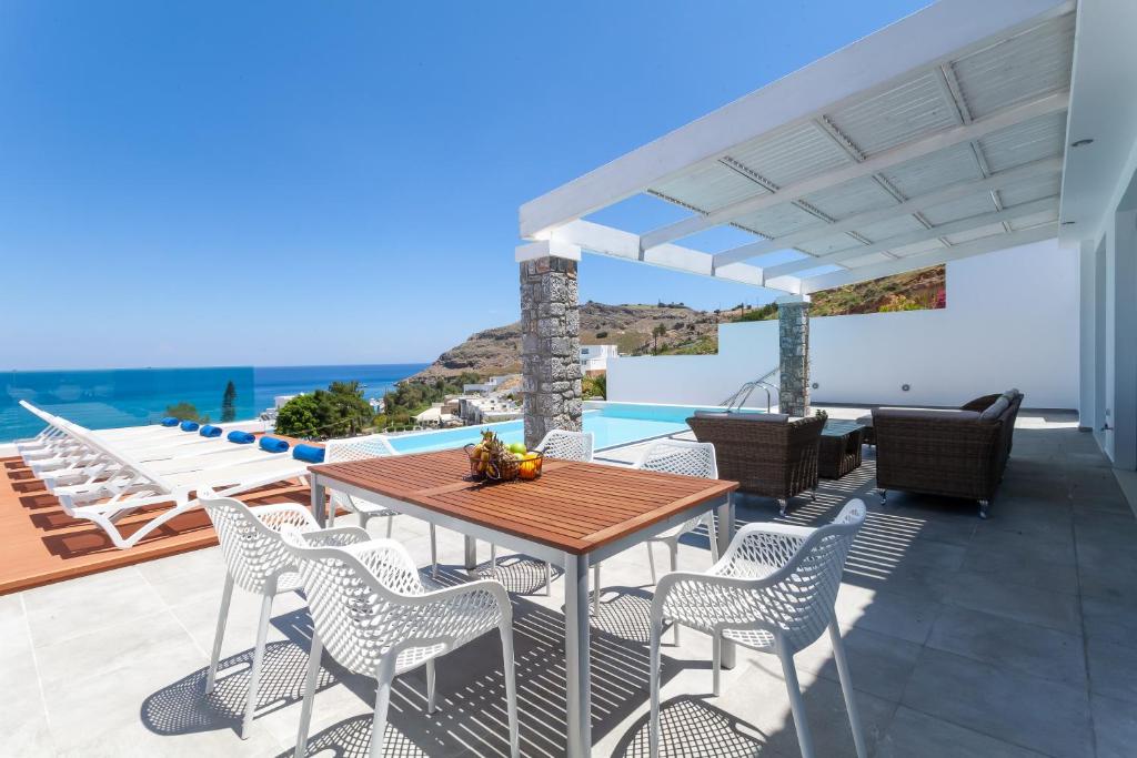 a patio with a table and chairs and a view of the ocean at Luxury Sunrise White Villa in Lindos