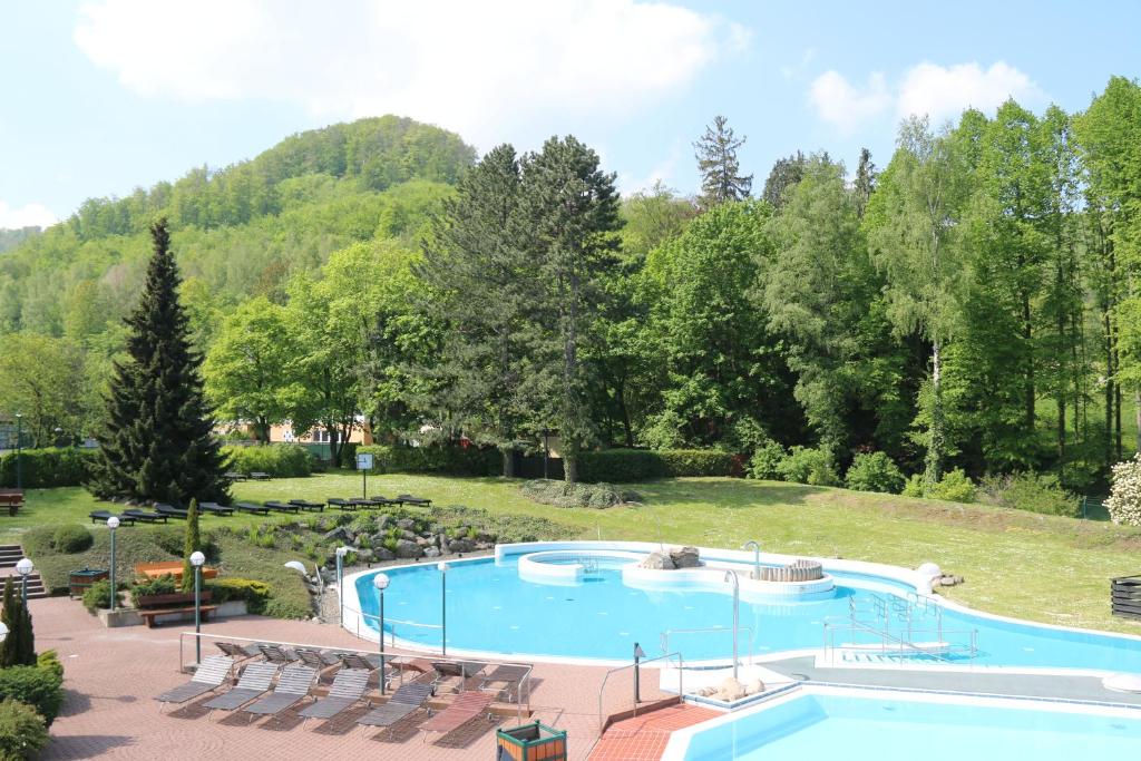 a large swimming pool in a park with chairs and trees at Solehotel Winterberg in Bad Harzburg