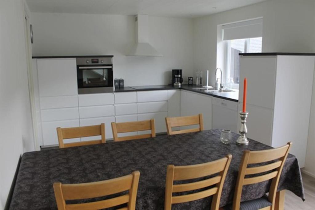 a kitchen with a table and chairs and a kitchen with white cabinets at Private Spacious Home in City Center in Klaksvík