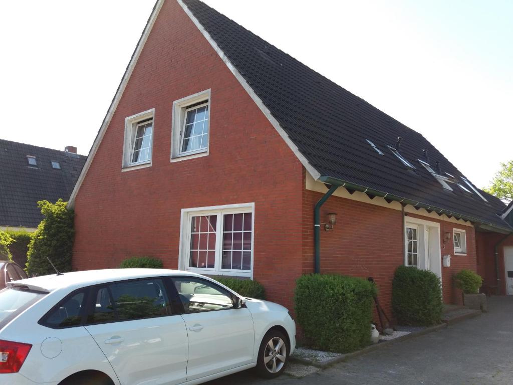 a white car parked in front of a red brick house at Pension-Stürrad in Neuharlingersiel