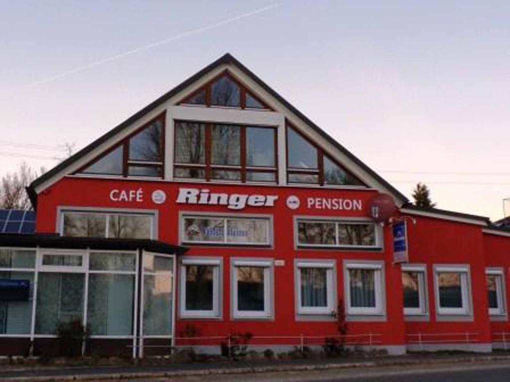 een rood gebouw met een bord vooraan bij Cafe und Pension Ringer in Vilseck