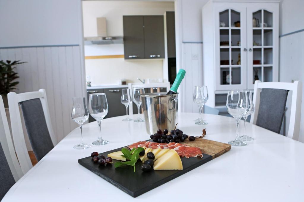 uma mesa branca com copos de vinho e um prato de comida em Apartman Charlie em Vrsi