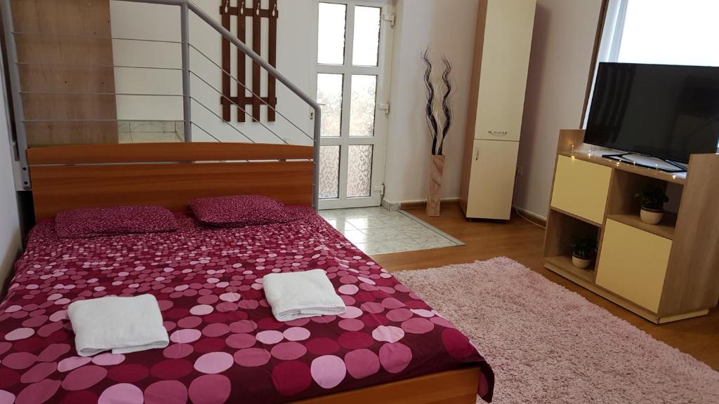Cette chambre comprend un lit avec des draps violets et une télévision. dans l'établissement Lend one room house, à Miercurea-Ciuc