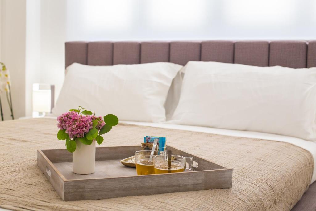 un vassoio con due bevande e un vaso con fiori su un letto di SuitesGaribaldi IUN R9481 a Cagliari