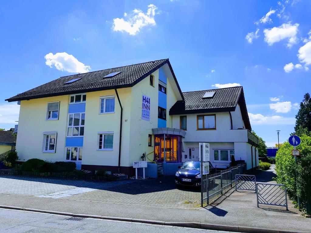 une maison blanche avec une voiture garée devant elle dans l'établissement H41 Inn Hotel Garni Freiburg, à Fribourg-en-Brisgau